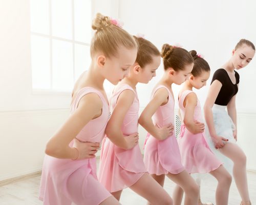 Young ballet teacher and students ballerinas in dance class. Girls are engaged in choreography in the ballet school, copy space